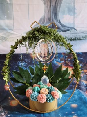 représentation d'une composition de fleurs en bougie moulée sur support en cercle avec suspension d'un attrape soleil animal totem chouette